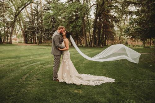 Bride and groom embrace on the lawn of the Norland Estate, an Alberta wedding venue