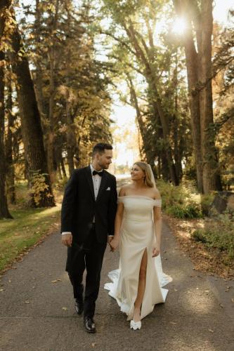 A couple walking down the tree-lined laneway during a fall wedding